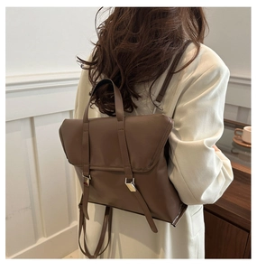 Deep brown matte PU leather flap backpack with silver buckles worn by a model in a minimal setting