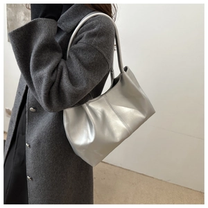 Silver metallic tote bag shown on a model wearing a grey wool coat against a plain wall