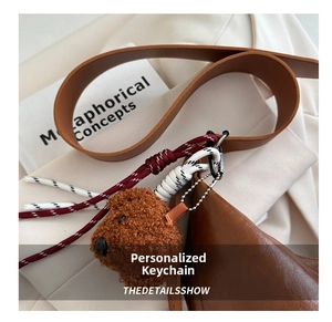 Détail d'un pendentif ours en peluche marron avec corde tressée sur fond minimaliste