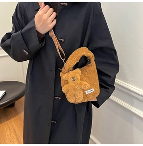 Brown plush teddy bear bucket bag with adjustable nylon strap shown on a model's shoulder