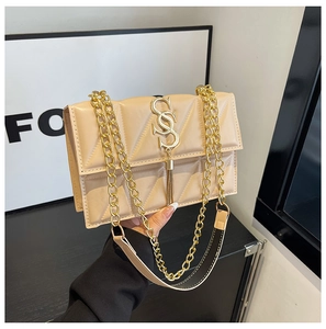 Detail of beige quilted shoulder bag with gold 'S' buckle, tassel, and chain strap