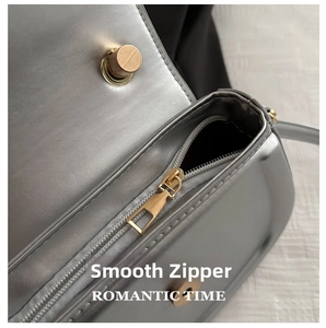 Detailed macro shot of silver metallic shoulder bag with smooth golden metal zipper and clasp