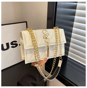 Detail of white quilted crossbody bag featuring gold S-shaped hardware and elegant tassels