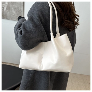 Detail of white PU leather tote bag with vertical stitching shown on model's shoulder