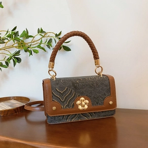 Sac bandoulière vintage avec boucle florale dorée sur un bureau en bois classique
