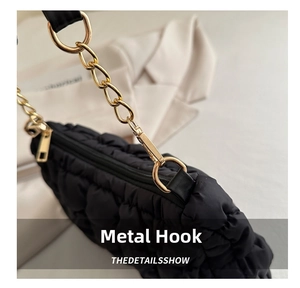 Close-up of a black quilted cloud bag showing golden metal chain hooks and zipper detail