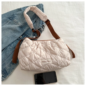 Detail of quilted puffer bag showing fashion label and adjustable brown shoulder strap
