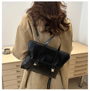 Model view of black matte leather tote bag with thin straps and metallic buckles
