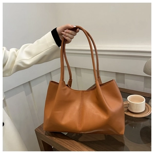 Close-up of brown faux leather tote bag with pleated design and large capacity details