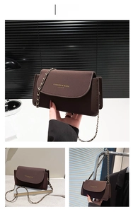 Détail du sac bandoulière en cuir café avec chaîne dorée et logo de marque gravé