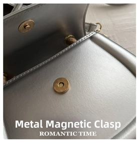 Detail shot of the magnetic snap closure with gold grid texture on a silver leather bag