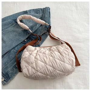 Detail of cream quilted tote bag featuring brown strap and soft padded diamond texture