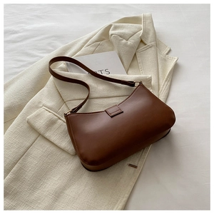 Brown leather baguette bag on a white tweed jacket with premium minimalist aesthetics