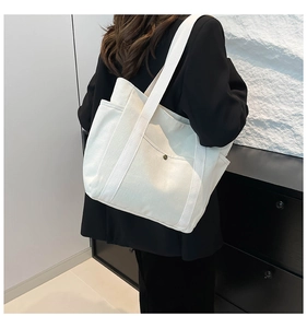 Detail of large canvas tote bag showing wide shoulder strap and side pocket design