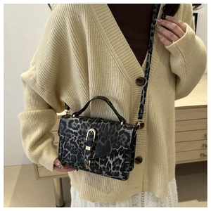 Detail of leopard print crossbody bag with gold U-shaped buckle on a female model