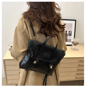Detail of black matte leather backpack with silver buckles and retro strap design