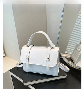 Detailed close-up of white lychee pattern leather bag with golden round metal buckle