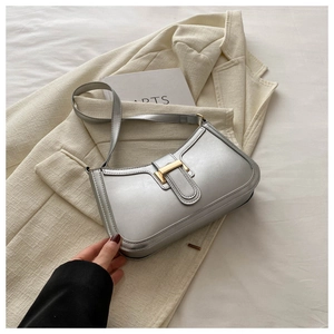 Close-up of silver baguette shoulder bag with metallic finish and gold buckle detail