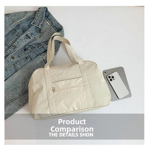 Detail of cream nylon travel tote bag showing front zipper pocket and wide handles