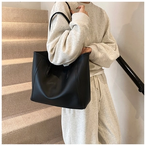 Detail view of reinforced side stitching on a minimalist black leather tote bag