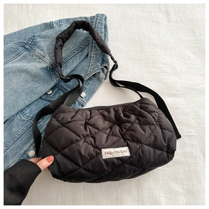 Detail view of black quilted crossbody bag with FASHION BAG label on textured background