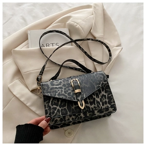 Detail of leopard print crossbody bag with gold metal clasp on beige blazer background