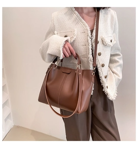 Detail view of brown PU leather tote bag with metal handles and adjustable shoulder strap