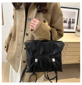 Detailed view of a black faux leather backpack with silver buckles worn in a cozy room