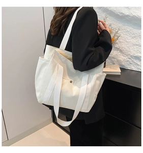 Detail view of large canvas tote bag showing side pockets and reinforced strap on a model