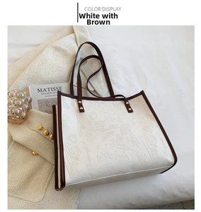 Close-up of white and coffee tote bag with embossed graffiti on a white bed background