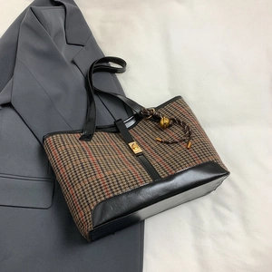 Chic houndstooth wool tote bag with red stripes and black leather handles on a suit