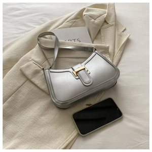 Detail of silver textured leather baguette bag with gold buckle on beige jacket