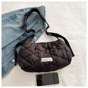 Detail of black quilted puffer bag showing soft rhombus texture and fashion label