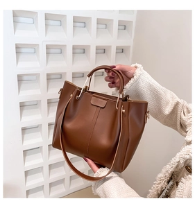 Macro detail of dark brown leather tote bag showing gold metal handle and rich texture