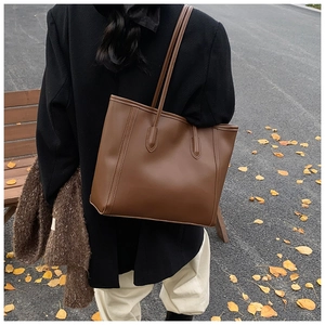 Detail of dark brown matte leather tote bag with vertical stitching for office use