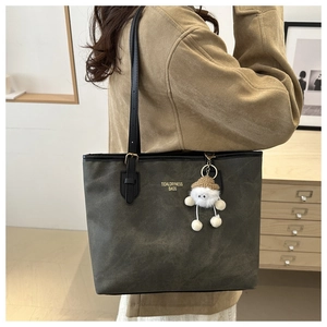 Detail of grey tote bag with gold lettering, shoulder straps and plush pendant charm
