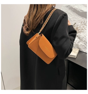 Détail d'un mini sac bandoulière en cuir marron avec chaîne dorée porté par un mannequin