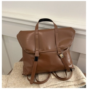 Detail of vintage brown leather backpack with silver metal buckles on a soft knit blanket
