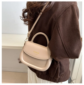 Detail view of cream saddle bag with gold metal hardware and adjustable shoulder strap