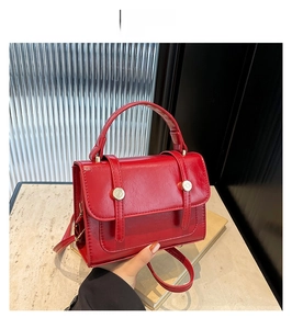 Detail of red vintage-style square handbag with lychee pattern and gold metal buckles
