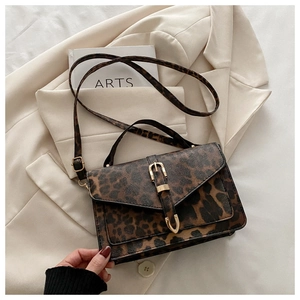 Close-up of leopard print PU leather bag with golden metal buckle on beige blazer