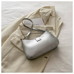 Detail of silver metallic shoulder bag showing glossy texture and curved flap design