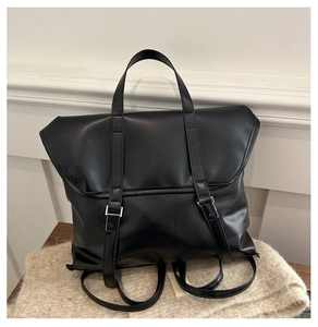 Detail of black faux leather backpack with metallic buckle straps and top handle