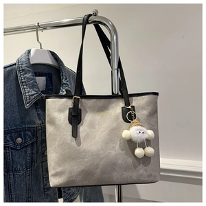 Detail of taupe marble-textured tote bag with black straps and cloud plush charm