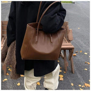 Detailed street style view of a large vintage brown leather tote bag on a wooden bench