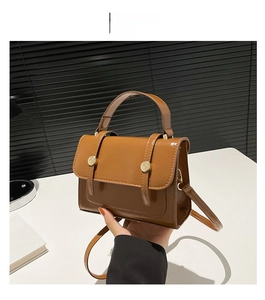 Detail view of the glossy brown vintage handbag with gold buckles and leather handle