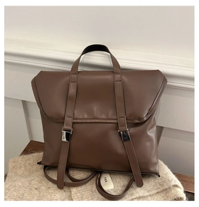 Detail view of the vintage brown leather backpack with silver metal buckles and top handle