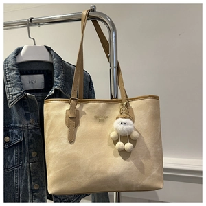 Detail of beige tote bag with Tidal dryness logo and cute plush charm pendant