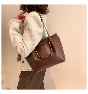 Detail of dark brown faux leather tote bag showing soft texture and shoulder strap