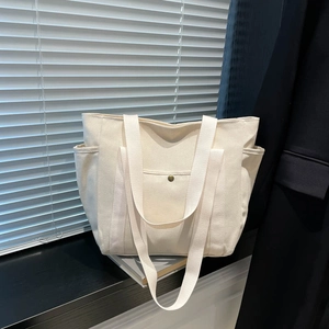Minimalist cream canvas tote bag with side pocket and metal button in aesthetic light
